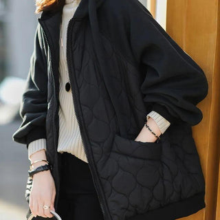 Veste matelassée à capuche noire, texture quiltée, zip frontal, poignets côtelés.