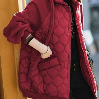 Veste matelassée à capuche rouge, fermeture zippée, motifs matelassés en relief.