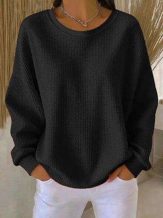 Pull en tricot noir à col rond, manches longues, texture maille et finitions côtelées.