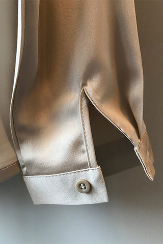 Blouse en satin champagne, gros plan sur revers de manche et bouton.