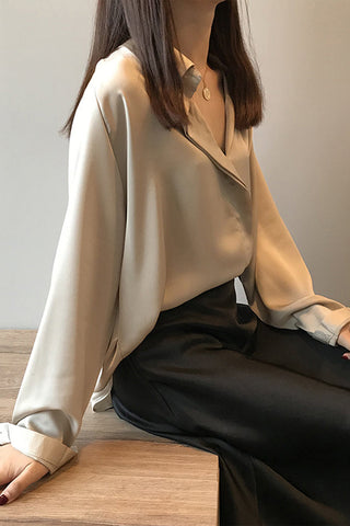 Blouse en satin champagne manches longues, col en V boutonné, tombé léger.