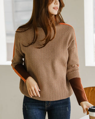 Blouse col montant motif chevrons noir et blanc, touches orange aux poignets, tenue avec jean.