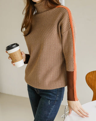 Blouse col montant manches longues, motif chevrons noir et blanc, empiècements orange sur les côtés.