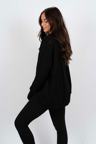 Sweat-blouse noir à col en V, vue de côté, bas côtelé et coupe ample.