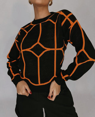 Blouse en maille noire à motifs géométriques orange, col rond, manches longues.