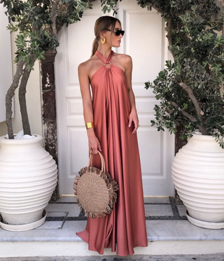 Robe maxi dos nu satinée rose, encolure halter nouée, longueur au sol