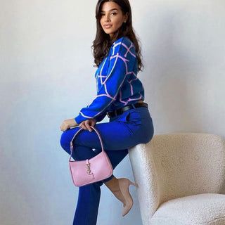 Blouse en maille bleue à motifs géométriques roses, col rond, manches longues, style pull.
