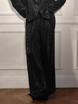 Veste longue à sequins noirs, fermeture croisée, pan long et bas évasé.