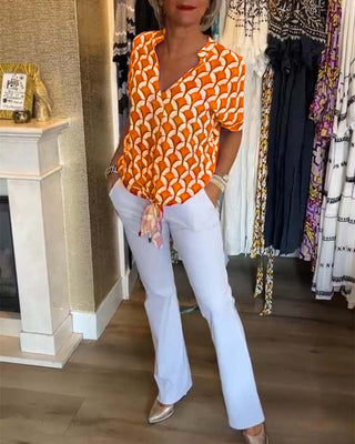Chemisier décontracté à manches courtes, encolure V, motif géométrique orange et blanc.