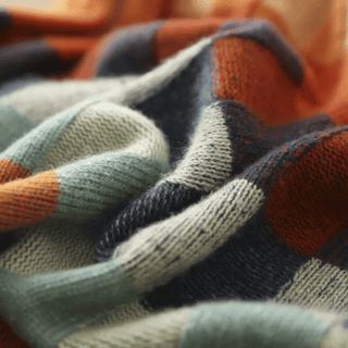 Gros plan sur la maille du pull à carreaux, texture tricotée visible.