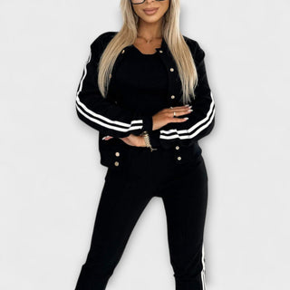 Ensemble veste et pantalon noir à bandes blanches, manches longues, boutons sur le haut.