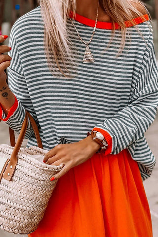 Blouse rayée bleu marine et blanche, bord orange côtelé au col et aux poignets.