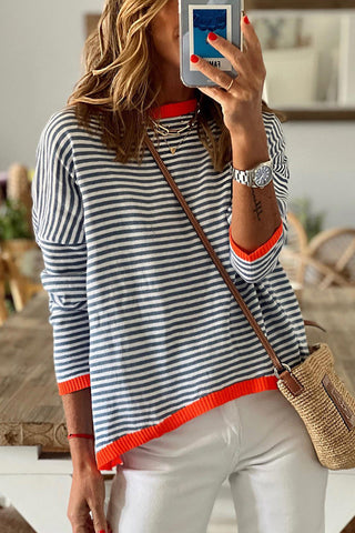 Blouse en maille à rayures bleu marine et blanches, bord orange au col et poignets.