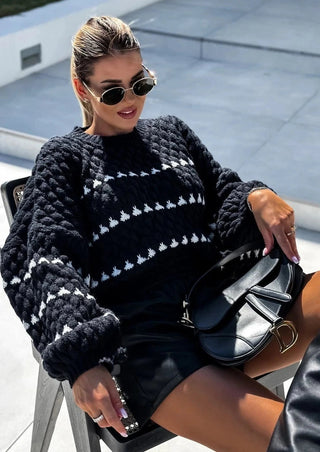 Pull en tricot noir à rayures blanches, manches bouffantes, col rond, maille épaisse.