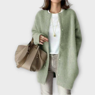 Veste ample en tissu vert, col rond, fermeture par boutons pression visibles.