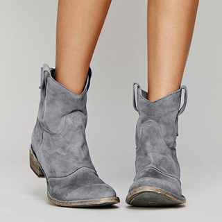 Bottes western en daim gris à hauteur de cheville, tirants latéraux, semelle contrastée.