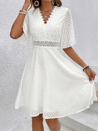 Robe blanche ample en dentelle, décolleté en V, motif chevrons et jupe évasée