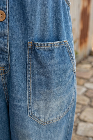 Poche plaquée sur salopette en jean bleu clair délavé, surpiqûres et rivets