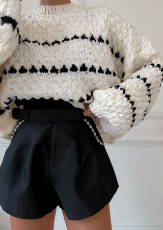 Pull en tricot vanille à rayures noires, col ras du cou, texture épaissie en maille.