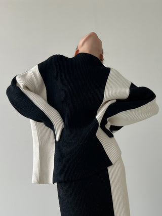 Ensemble jupe et blouse noire à col montant, finitions contrastées écru sur les manches.
