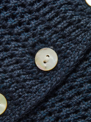 Bouton rond clair et tricot texturé bleu, gros plan sur la fermeture