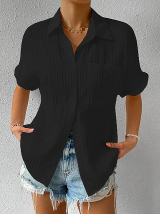 Chemisier noir ample à manches courtes, col chemise, boutonnage et poche poitrine