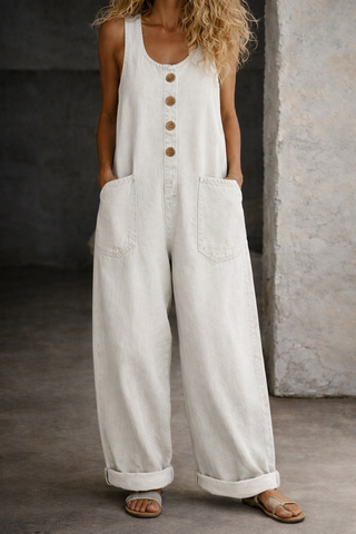 Salopette denim blanc sans manches, bouton central, grandes poches latérales, jambes amples