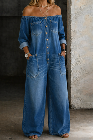 Combinaison longue en jean bleu, épaules dénudées, boutonnée, poches plaquées.