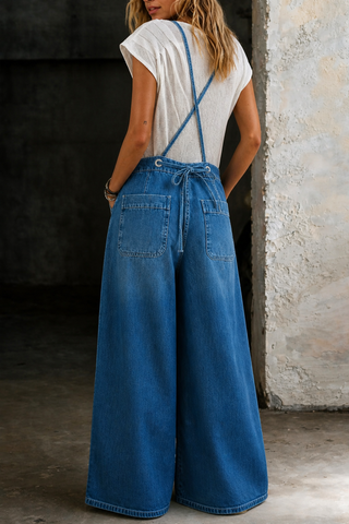 Salopette en jean bleu à jambes larges, bretelles croisées et lien à la taille