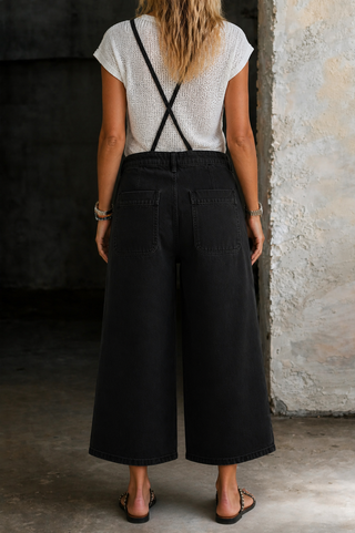 Salopette noire en jean à jambes larges, poches avant et taille boutonnée