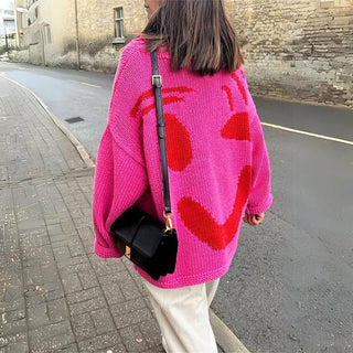 Pull en tricot épais rose oversize à motif graphique rouge, manches longues.