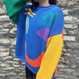 Pull en tricot épais bleu oversize à motif sourire multicolore, manches contrastées.