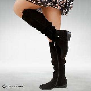 Bottes noires effet daim, tige haute, talon bloc, patte décorative sur le côté.