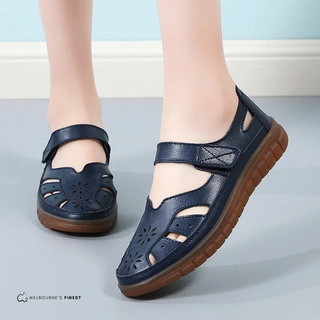 Chaussures orthopédiques réglables bleu foncé à velcro, semelle marron, ajourées.