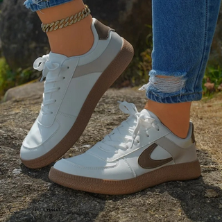 Baskets orthopédiques blanches avec semelle brune, lacets, logo bleu marine sur le côté.