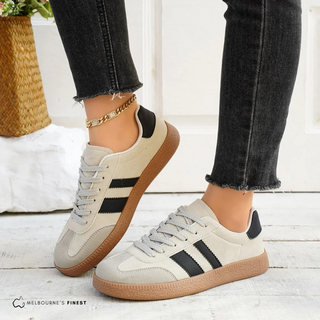 Chaussures orthopédiques Ruby™ beiges avec bandes noires et semelle en caoutchouc.