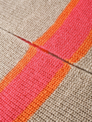 Détail de maille beige avec rayures orange, corail et rose fuchsia