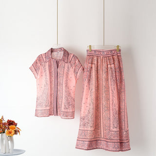 Ensemble blouse et jupe imprimées rose sur cintres : blouse col boutonné, jupe évasée.
