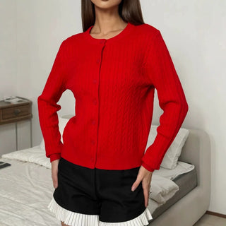 Cardigan rouge en tricot à câbles, col rond et boutonnage devant.