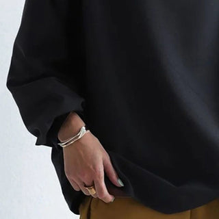 Pull femme noir à col montant, gros plan sur l’ampleur des manches et la coupe.