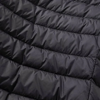 Doudoune matelassée noire, finition en bandes rembourrées et coutures visibles.
