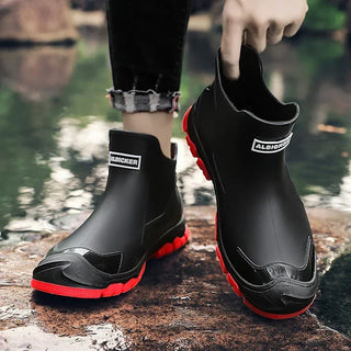 Bottines noires à enfiler, bout fermé, semelle crantée rouge, vue arrière avec logo.