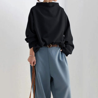 Pull femme noir à col montant, silhouette droite, manches longues amples.