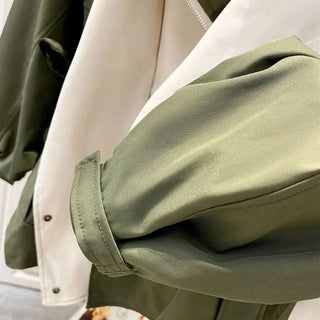 Manche et empiècement contrastés de veste vert olive, coutures visibles.