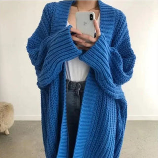 Manteau long bleu en maille épaisse, col châle, drapé, manches longues.