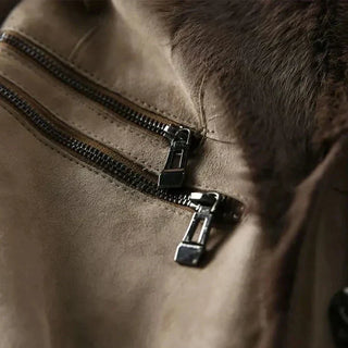 Fermeture zippée métal sur manteau en suède taupe avec bordure en fourrure.