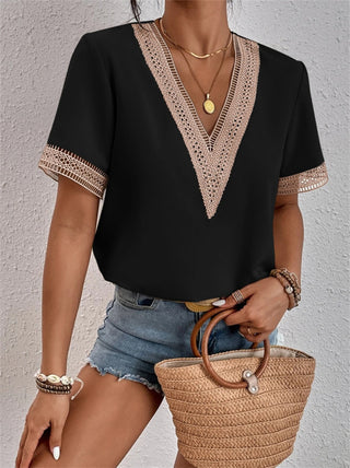 Blouse brodée à col en V, manches courtes, noir avec bordure beige dentelée.