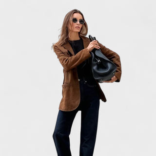 Manteau marron en daim, col veste, fermeture boutonnée, poches latérales visibles.
