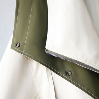 Détail manche et couture de veste bicolore, boutons métalliques et finition contrastée.