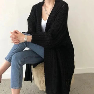 Manteau long en maille noire à col châle, manches longues, silhouette drapée.